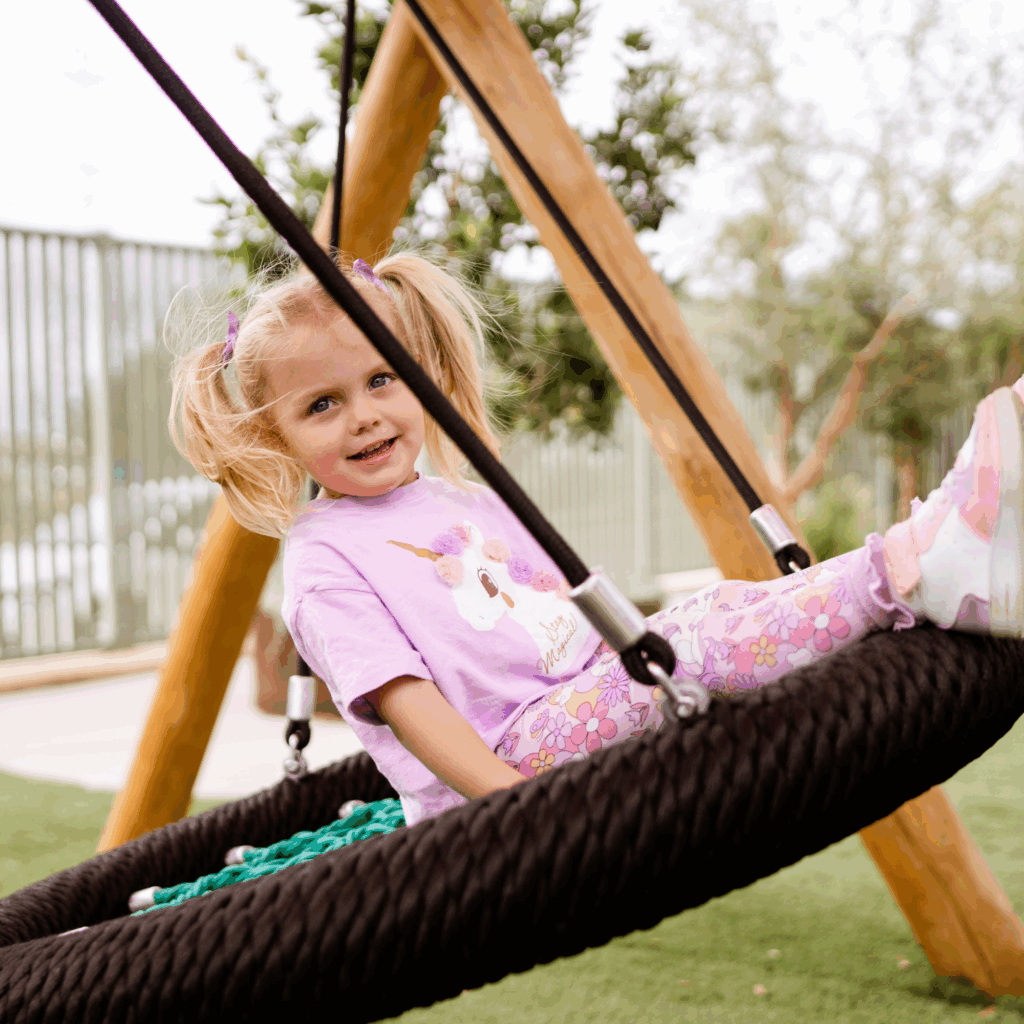 Little girl on a swing in a daycare playground
