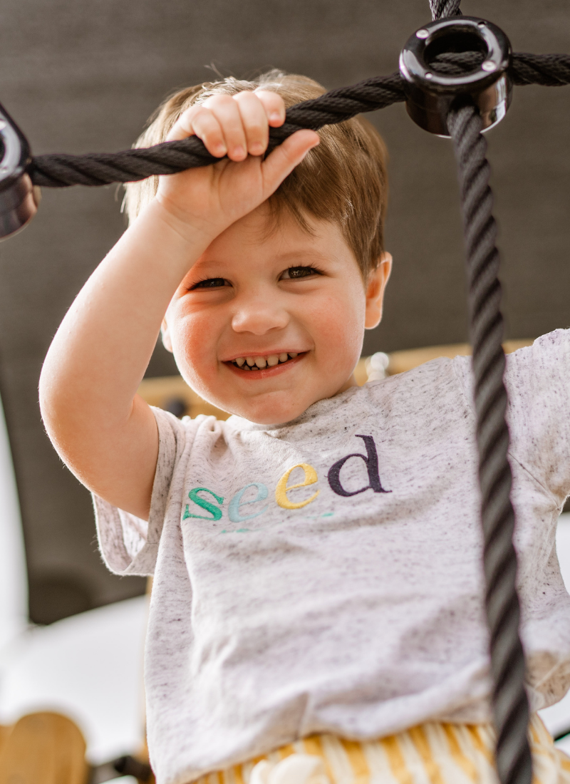 Little boy climbing on climbing frame in a daycare playground